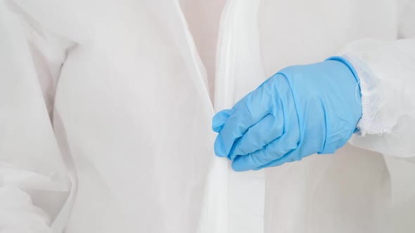 Closeup of Female Doctor Wearing and Zipping Protective Suit Against Viruses and Biohard