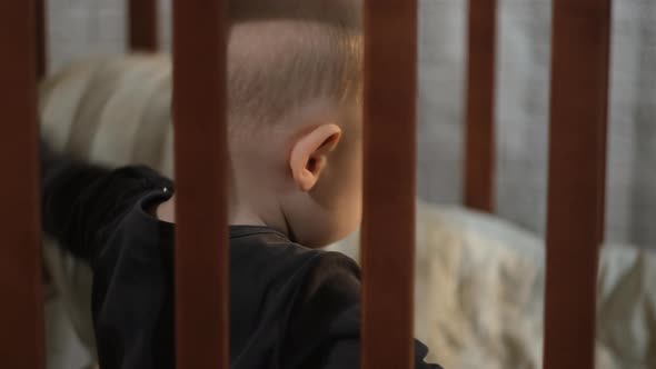Cute Little Caucasian Toddler Boy Sitting in Crib