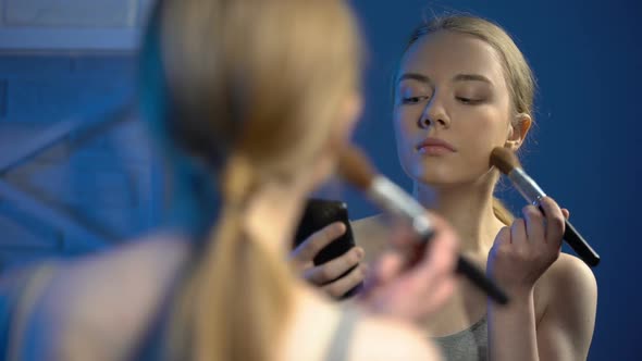 Young Female Doing Make-Up Watching Online Video on Smartphone