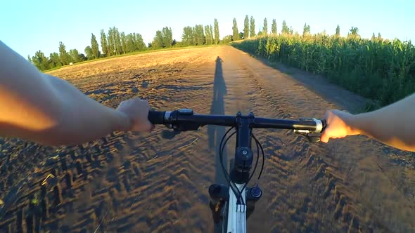 A Girl Rides a Bicycle on the Ground in a Summer Field During Sunset Sunrise