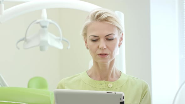 Woman Dentist Using Tablet Computer. Dental Professional Using Tablet Pc