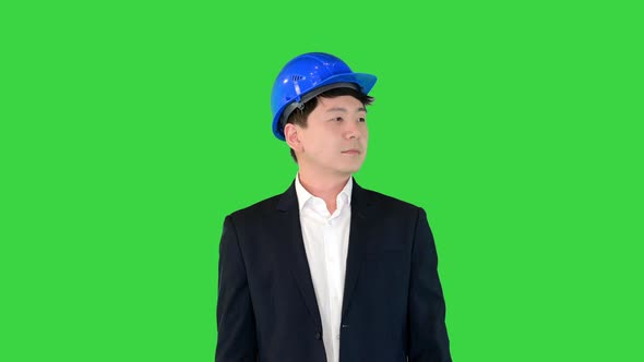 Asian Engineer in a Suit and Hardhat Standing with Hands Folded on a Green Screen Chroma Key