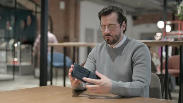 Young Man Checking Empty Wallet in Office