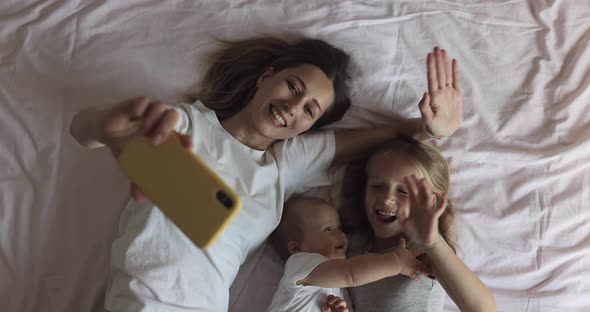 Happy Caucasian Mother and Kids Have Online Video Call with Father or Grandmother Via Mobile Phone