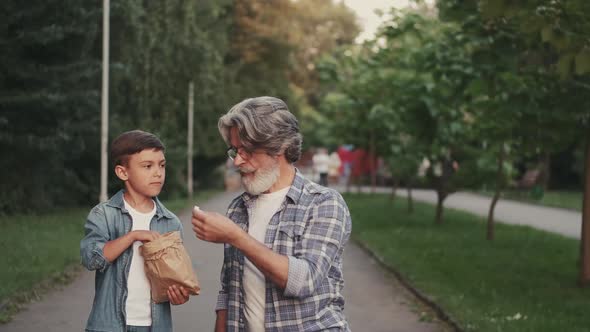 Grandson and Grandfather Eating Snack in a Park