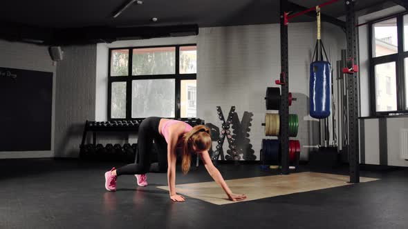 Athletic attractive woman doing cardio exercise burpee in the gym