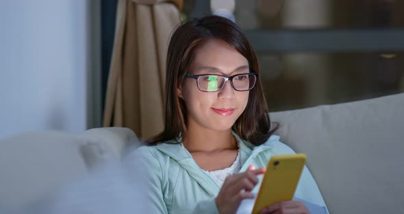 Woman with glasses and use of mobile phone at home in the evening