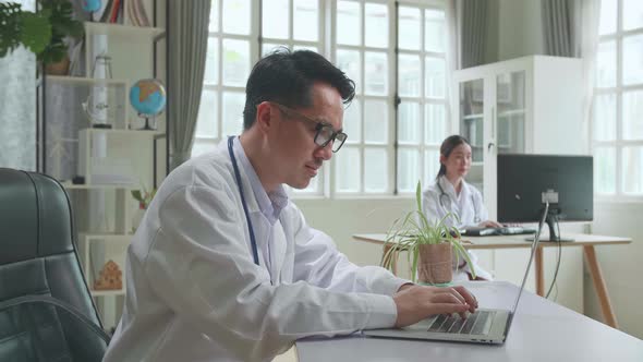 Asian Man Doctor Is Using Laptop Computer In Workplace. Medical Concept