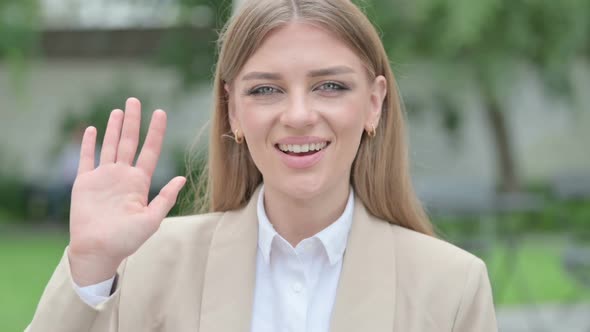 Outdoor Portrait of Young Businesswoman Waving at the Camera