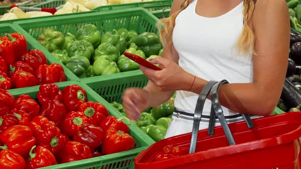 Woman Using Smart Phone While Shopping at the Supermarket