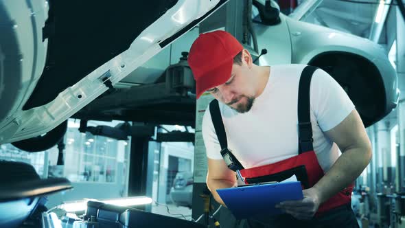 Auto Mechanic Examining a Car with a Tablet