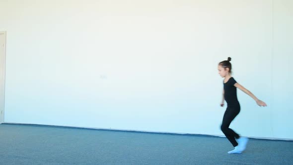 Young Lady in Black Tracksuit Practices Ballet Jumps