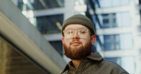 A Bearded Man Standing in the Courtyard of Office Center and Looking at Camera