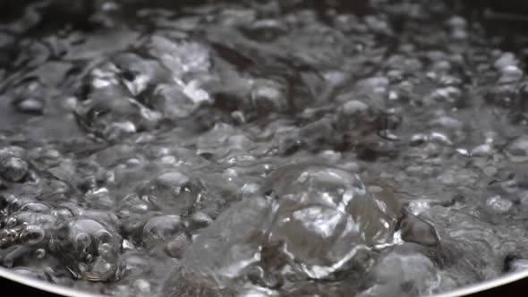 Slow Motion Shot of Boiling Water. Bubbles of Boiling Water Background. Cooking Concept