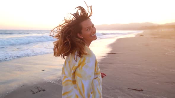 Happy and playful woman at the beach at sunset