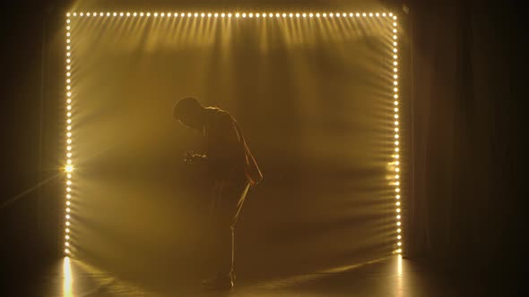 Silhouette of Musician in Ethnic African Costume Plays the Guitar in a Dark Studio. Black Barefoot