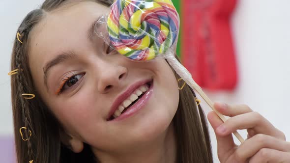 Cute Little Girl Holding a Colorful Lollipop Looking at the Camera