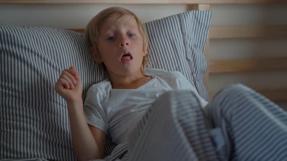 Sick Little Boy in a Bed. Superslowmotion Shot of a Boy Coughing in Bed