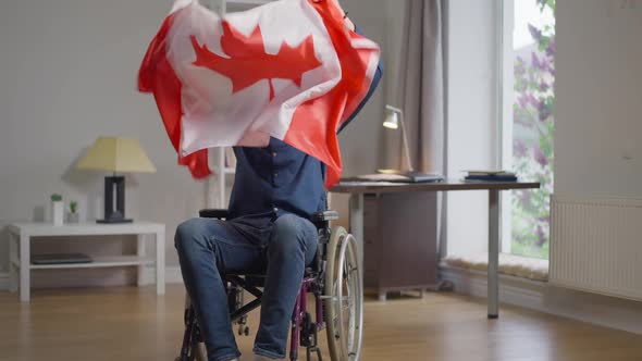 Front View Joyful Smiling Disabled Man in Wheelchair Shaking Canadian Flag Rejoicing Success