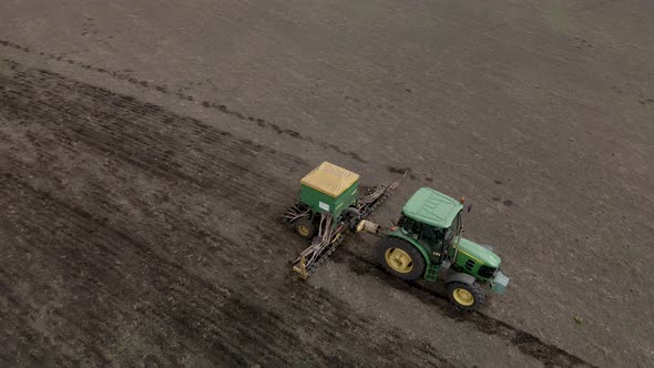 Tractor plows the field during agricultural sowing