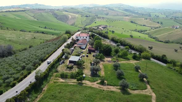 Aerial shot of a hilly field landscape with a van traveling on a road