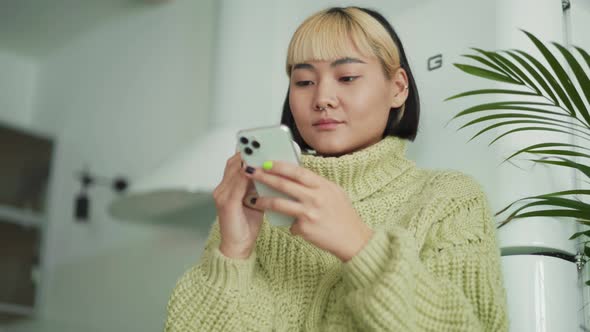 Thinking Asian woman looking at phone and to the side