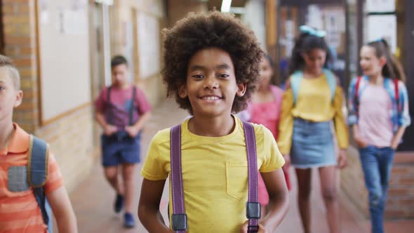 Portrait of happy african american schoolboy standing in corridor looking at camera