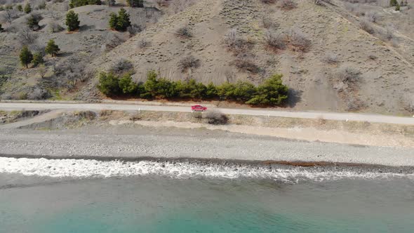 Aerial View of Red Car Moving Along Road Near Sea