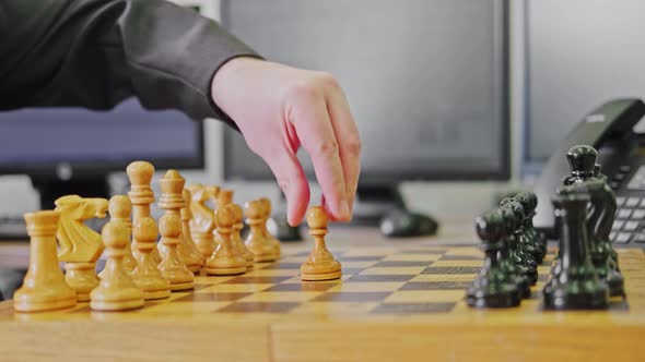 A businessman man with a chess piece pawn in his hands is working on a computer keyboard