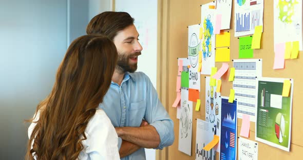 Business colleagues interacting with each other near bulletin board