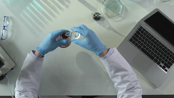 Lab Assistant Conducting Investigations for Presence of Sediments in Liquid