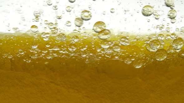 Golden and White Background of Poured Sesame Oil and Black Cumin Oil, Resulting in Air Bubbles and