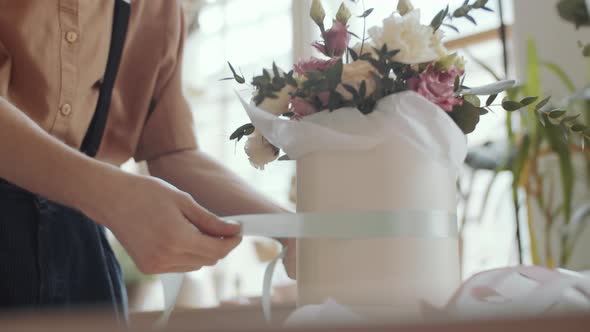 Male Florist Decorating Flower Arrangement in Hatbox with Ribbon