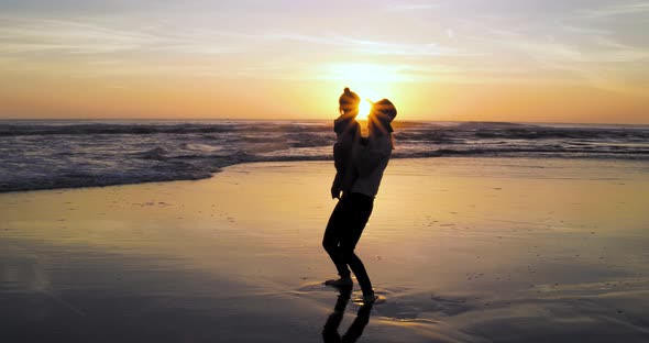 A mother enjoys vacation with there child during sunset at the beach as she throws her child up in t