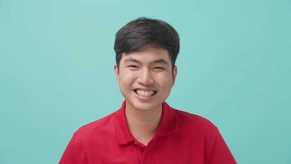 Portrait of attractive Asian young man smile and laugh in studio with isolate blue screen background