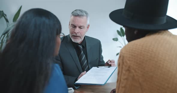 Multi ethnic couple discussing contract with sales agent