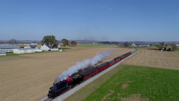 Aerial View of an Antique Restored Steam Locomotive with Passenger Cars Pulling into Freight Yard