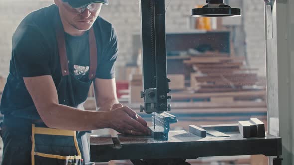 Man in a Carpentry Workshop Cutting Pieces of the Wooden Detail Using a Static Cutting Machine