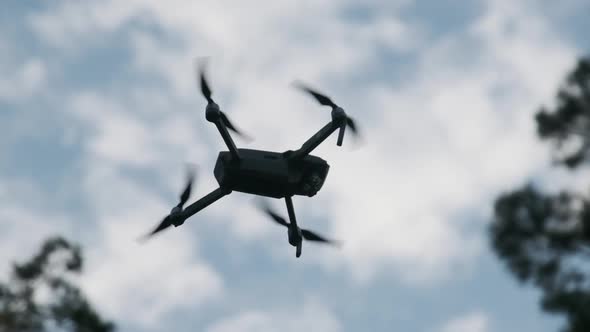 Drone Hangs in the Air Against the Blue Sky, View From Below. Slow Motion 240 Fps