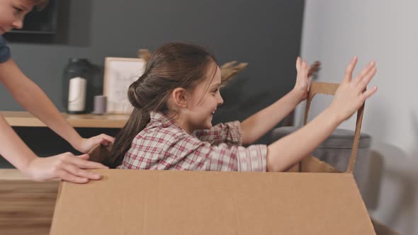 Siblings Playing With Cardboard Car