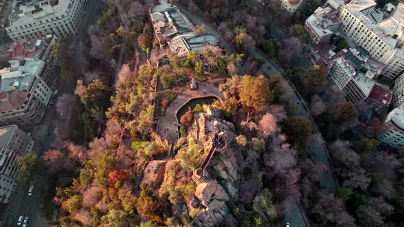 Aerial rising over top of Santa Lucia Hill covered with autumnal trees and Pedro de Valdivia Square