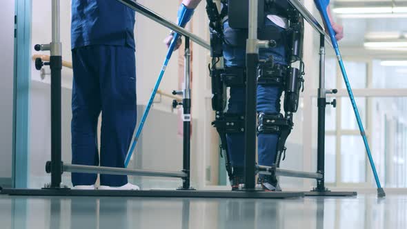 A Person is Learning to Walk in the Exoskeleton with Medical Help