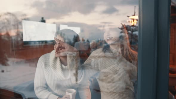 Two Girls Looking Through the Window at Snow Covered Neighborhood