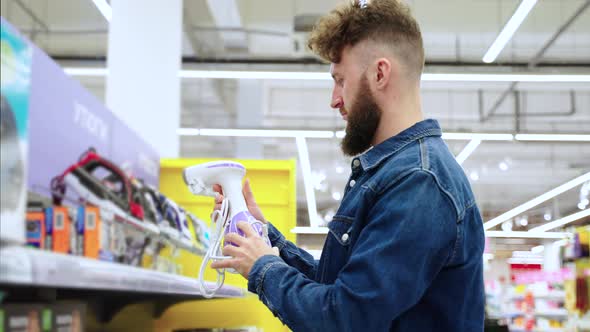 Male Shopper is Choosing Clothes Steamer in Home Appliance Store