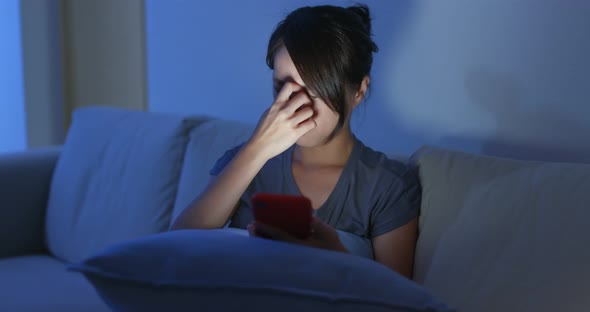 Woman use of mobile phone at night and sit on sofa at home