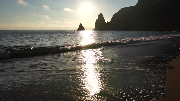 A Red Burning Sunset Over the Sea with Rocky Volcanic Cliff