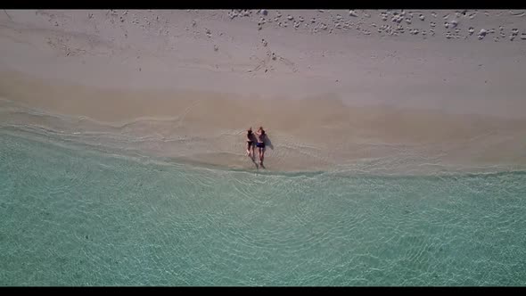 Romantic couple sunbathe on idyllic coast beach journey by blue lagoon with white sandy background o