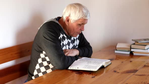 Senior Man Praying Reading an Old Bible in His Hands