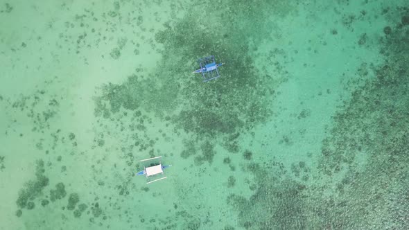 Slowly rotating aerial bird's eye view of banca boats sitting in Badian Bay off the coast of Moalboa