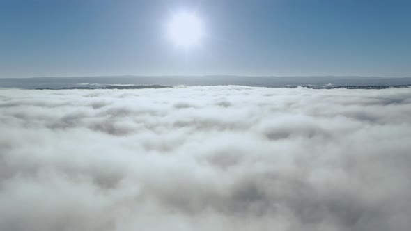 Clouds and sun, drone rises above thick fog over the beautiful ocean of clouds at sunrise. Amazing n